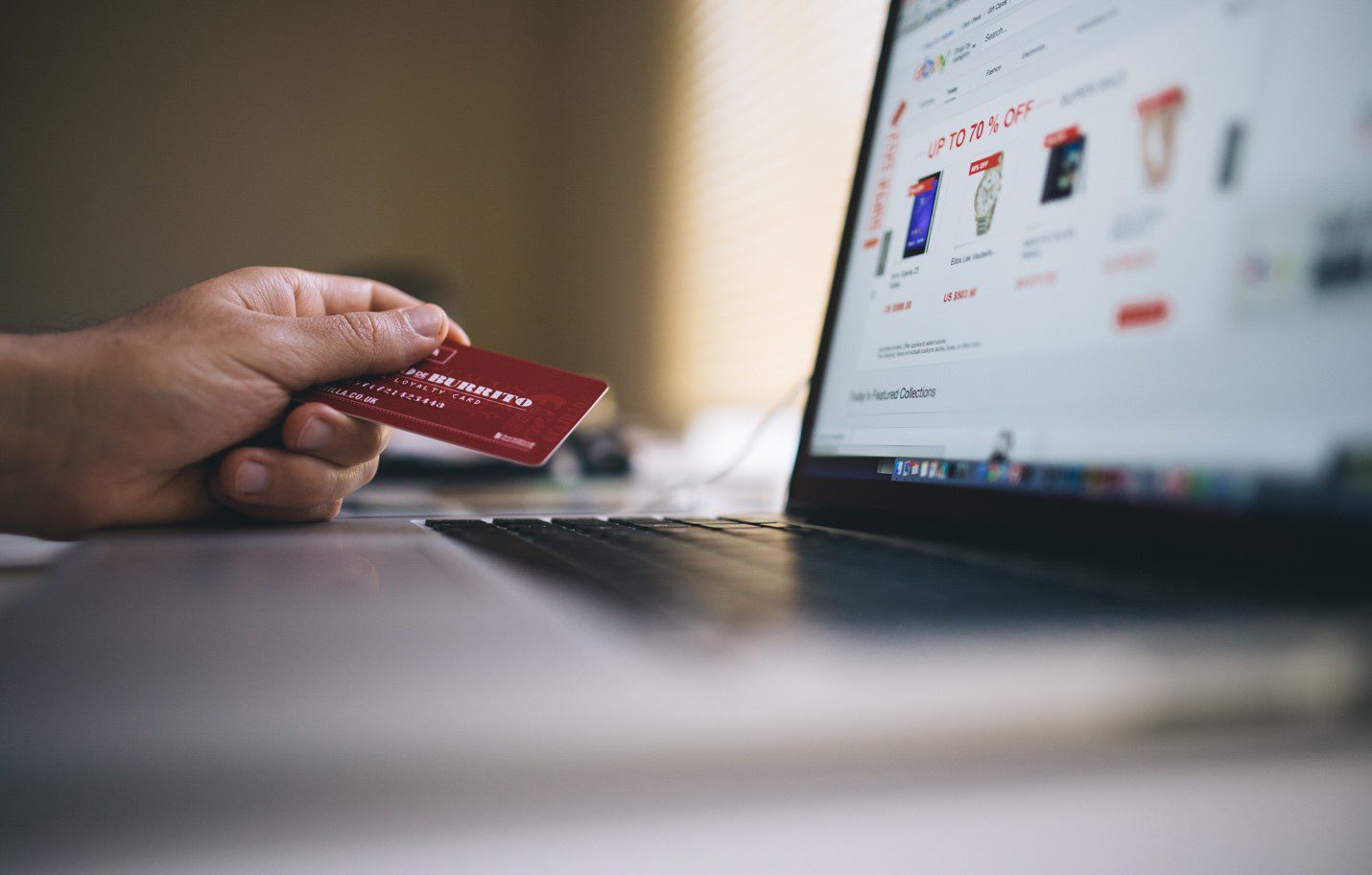 Person holding credit card in front of laptop