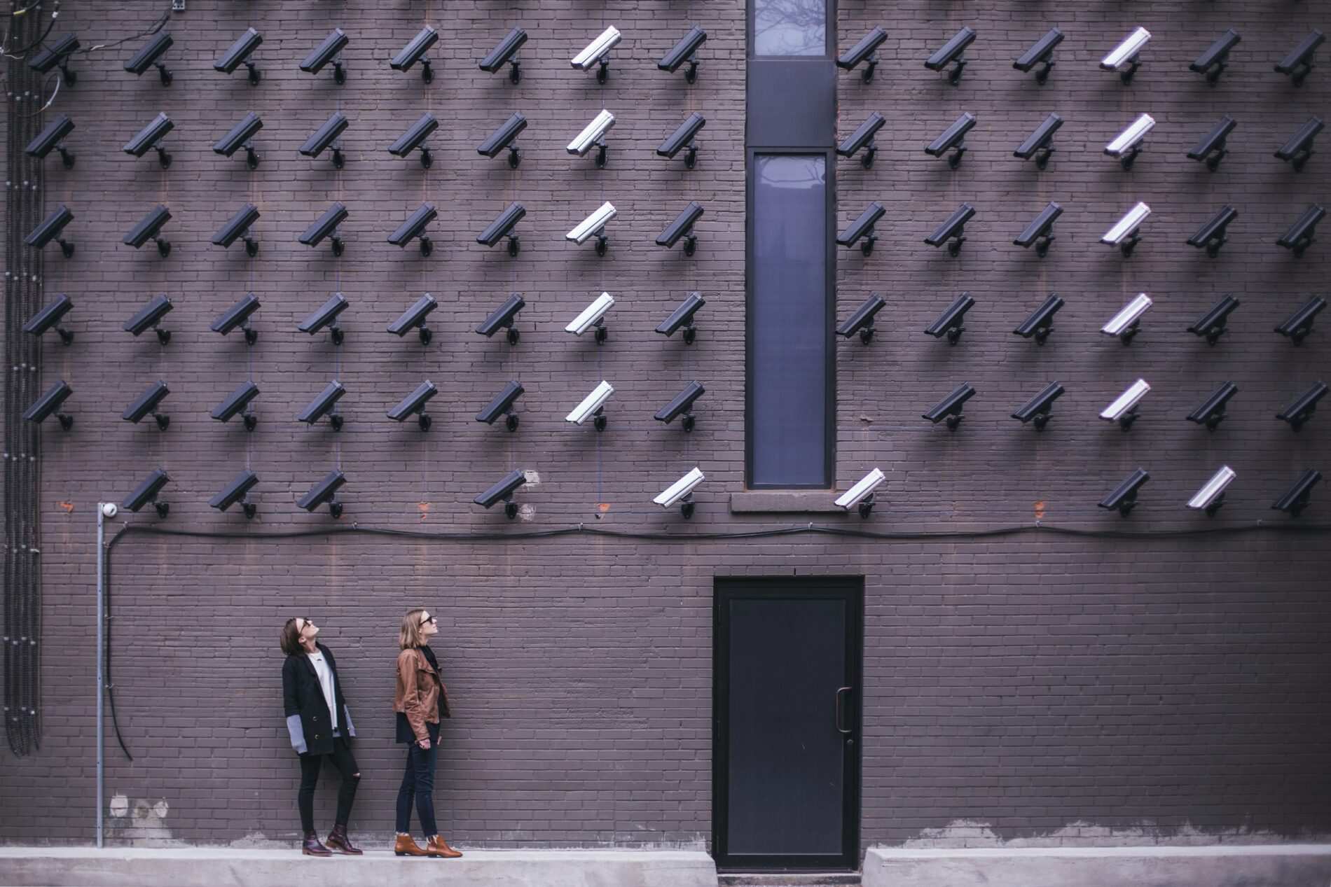 Two people looking up at security cameras on a wall